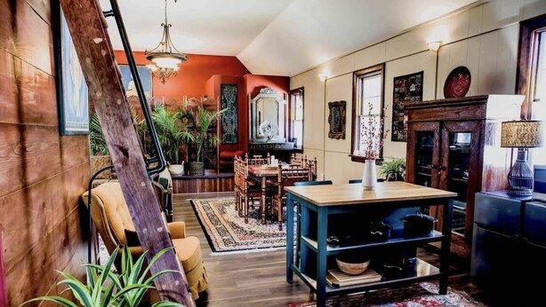 A cozy living room with a wooden floor, a dining area with a table and chairs, and a large mirror on the wall. - Your Downtown Oasis 14-foot ceilings, luxury living. Relaxing outdoor spaces (Elora)