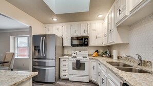 A modern kitchen with white cabinets, stainless steel appliances, and a granite countertop.