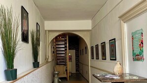 A hallway with stone flooring, a wooden bench, a table with papers, and framed pictures on the walls. - Apartment in Verdun, "La Scène du 66" (Verdun)