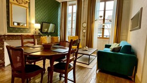 A dining area with a wooden table and chairs, a green sofa, and a chandelier. - Apartment in Verdun, "La Scène du 66" (Verdun)