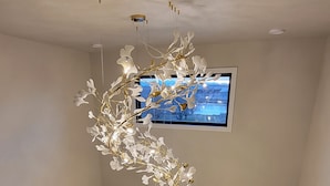 Un interior moderno con una escalera, una lámpara decorativa y un televisor montado en la pared.