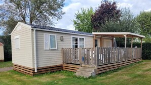 Une maison mobile dotée d’un porche couvert et d’une terrasse clôturée.