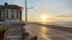 Un chemin pavé qui mène à une plage, avec un coucher de soleil en arrière-plan.