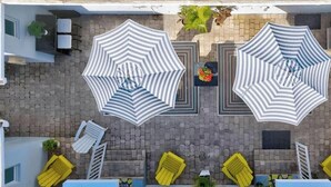 A rooftop terrace with two large striped umbrellas, yellow lounge chairs, and a small pool area. - Sun-kissed Charm: Beachside Hollywood Studio (Hollywood)