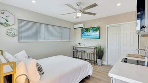A bedroom with a bed, a desk, and a TV. - Sun-kissed Charm: Beachside Hollywood Studio (Hollywood)