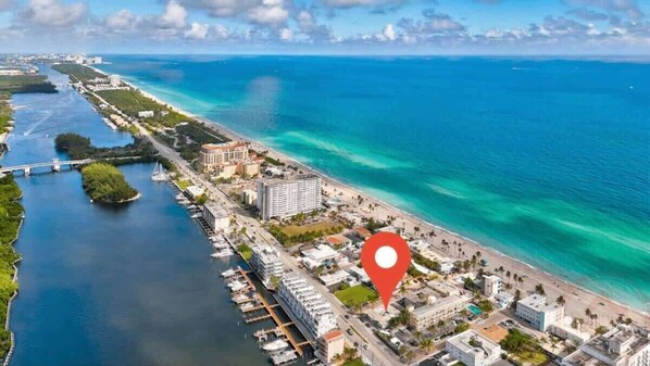 An aerial view of a coastal city with a marina, a bridge, and a beach.