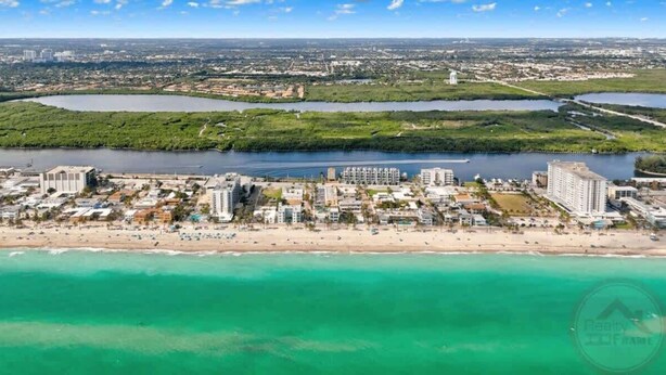 Vista aérea de una ciudad costera con playa, edificios y cuerpos de agua.