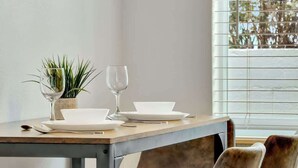 A dining table with white plates, a wine glass, and a small plant. - Coastal Retreat ONLY 1 block from the beach! (Hollywood)