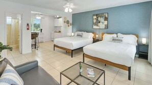 A hotel room with two beds, a sofa, a coffee table, and a view of the kitchen and dining area. - Coastal Retreat ONLY 1 block from the beach! (Hollywood)