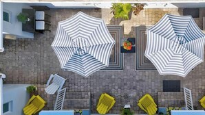 A rooftop terrace with two large striped umbrellas, yellow lounge chairs, and a small pool area. - Coastal Retreat ONLY 1 block from the beach! (Hollywood)