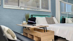 A modern bedroom with a bed, a desk with a laptop, and a window with blinds. - Sunny Serenity: Hollywood Studio Getaway (Hollywood)