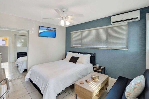 Una habitación de hotel con una cama, un escritorio, una silla, un televisor y un aire acondicionado.