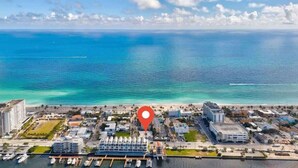 Luftaufnahme einer Küstenstadt mit Hafen, Gebäuden und Strand.