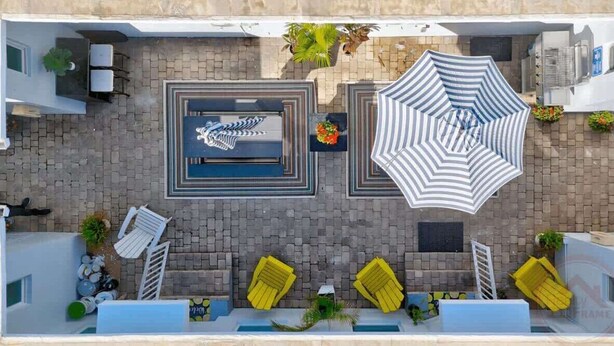 Eine Dachterrasse mit Pool, Liegestühlen und Sonnenschirmen, aufgenommen aus der Vogelperspektive.