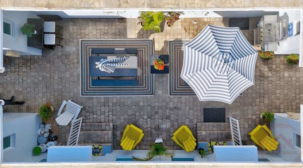 Vista aerea di una terrazza sul tetto con piscina, lettini e ombrelloni.