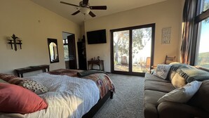A bedroom with two beds, a ceiling fan, a large window with a view, and a motivational quote on the wall. - Guesthouse in very private location in Malibu with ocean views!
 (Malibu)