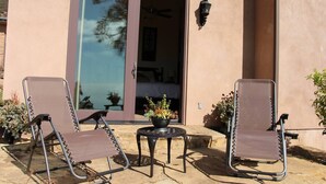 A patio with two lounge chairs and a small table, a sliding glass door, and a potted plant. - Guesthouse in very private location in Malibu with ocean views!
 (Malibu)