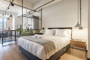 Une chambre moderne avec un grand lit, une table de chevet et une vue sur l’extérieur.