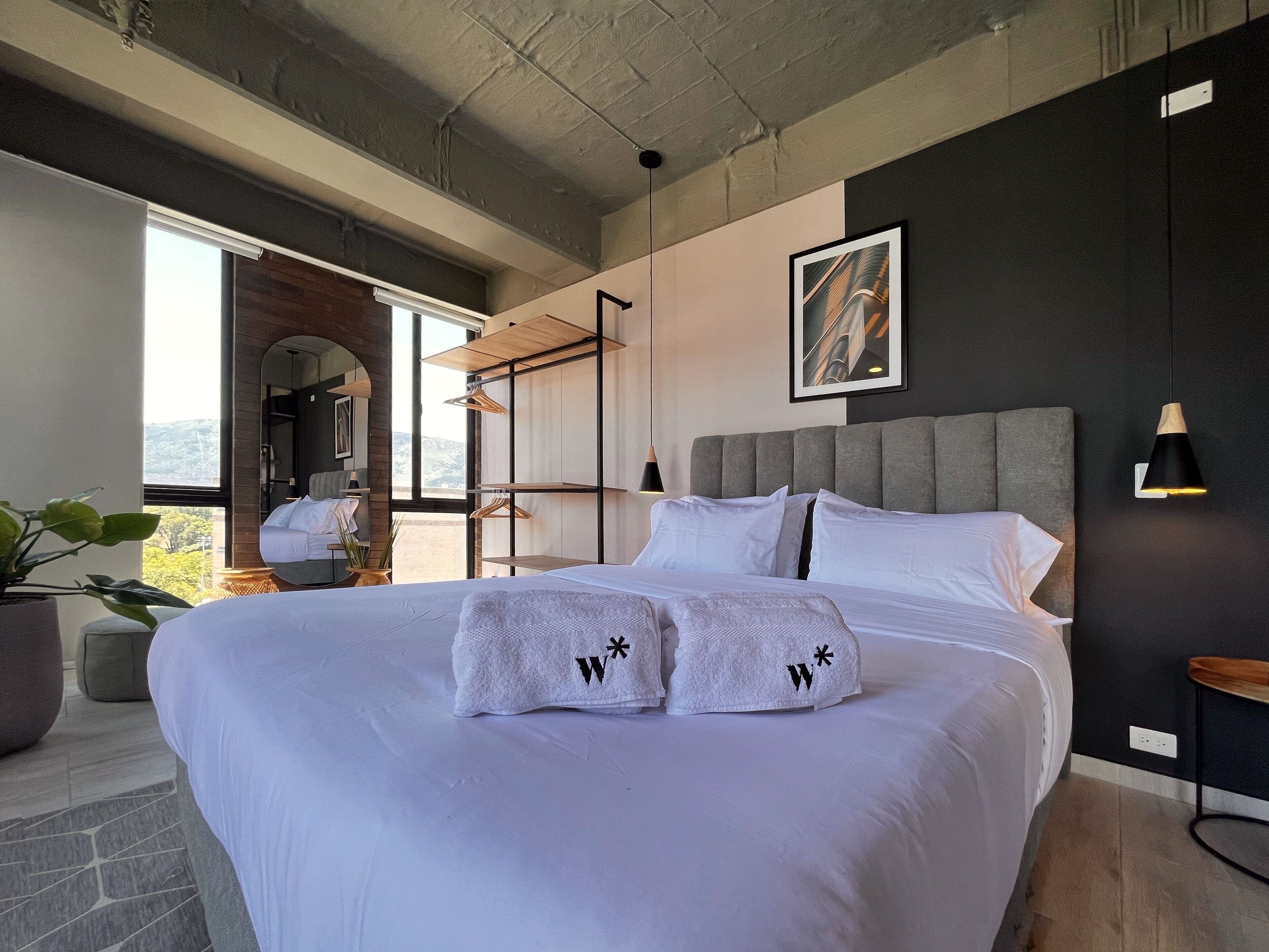 A modern bedroom with a large bed, a view of the outdoors, and a unique ceiling design.