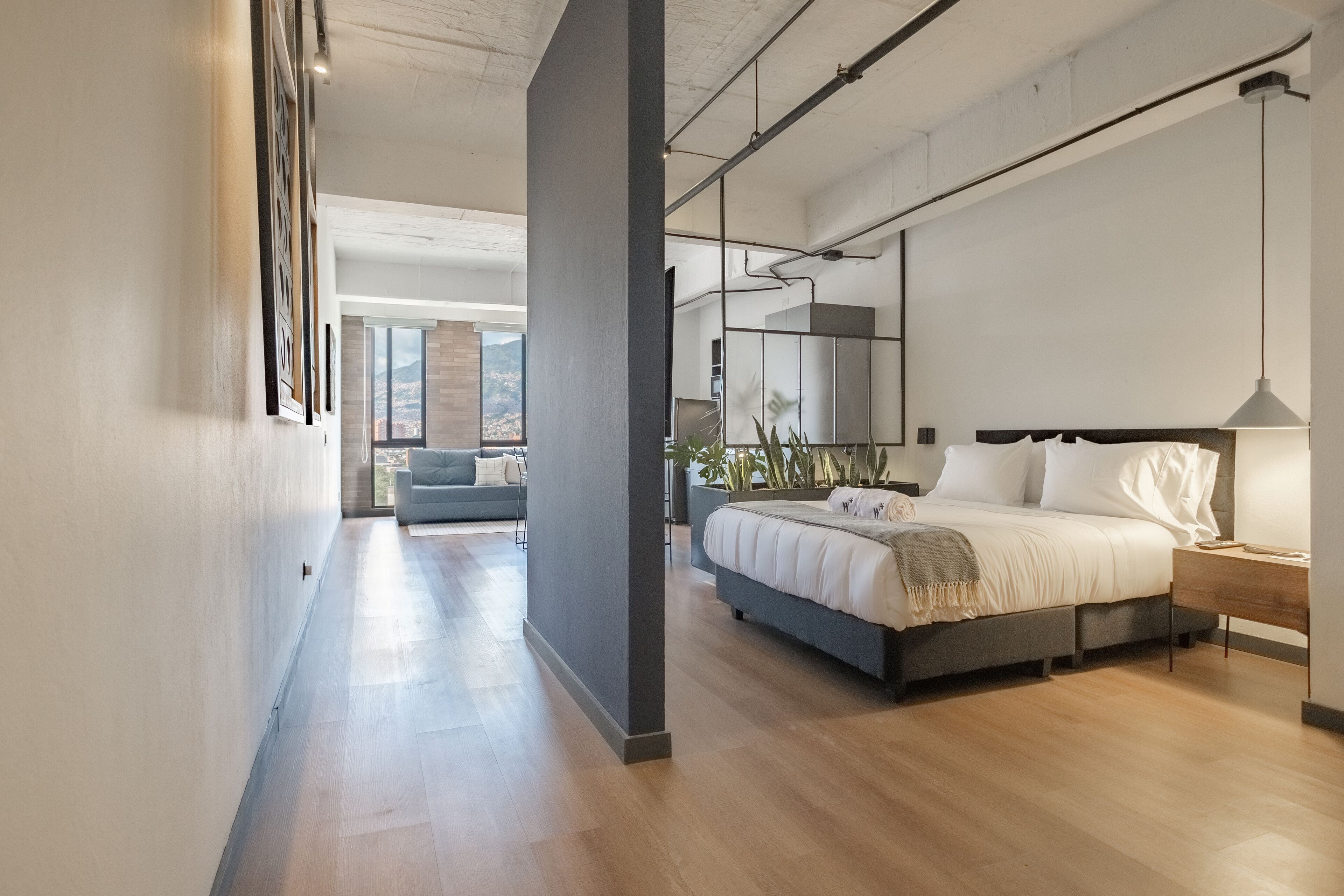 A modern bedroom with a large bed, bedside tables, and a view of a cityscape.