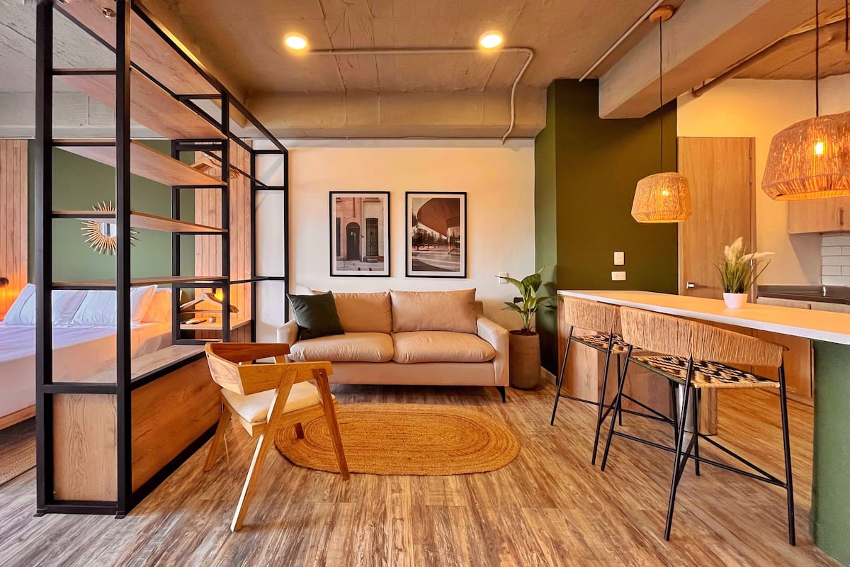 Een moderne woonkamer met een bank, een houten salontafel en een eetgedeelte met een bar.
