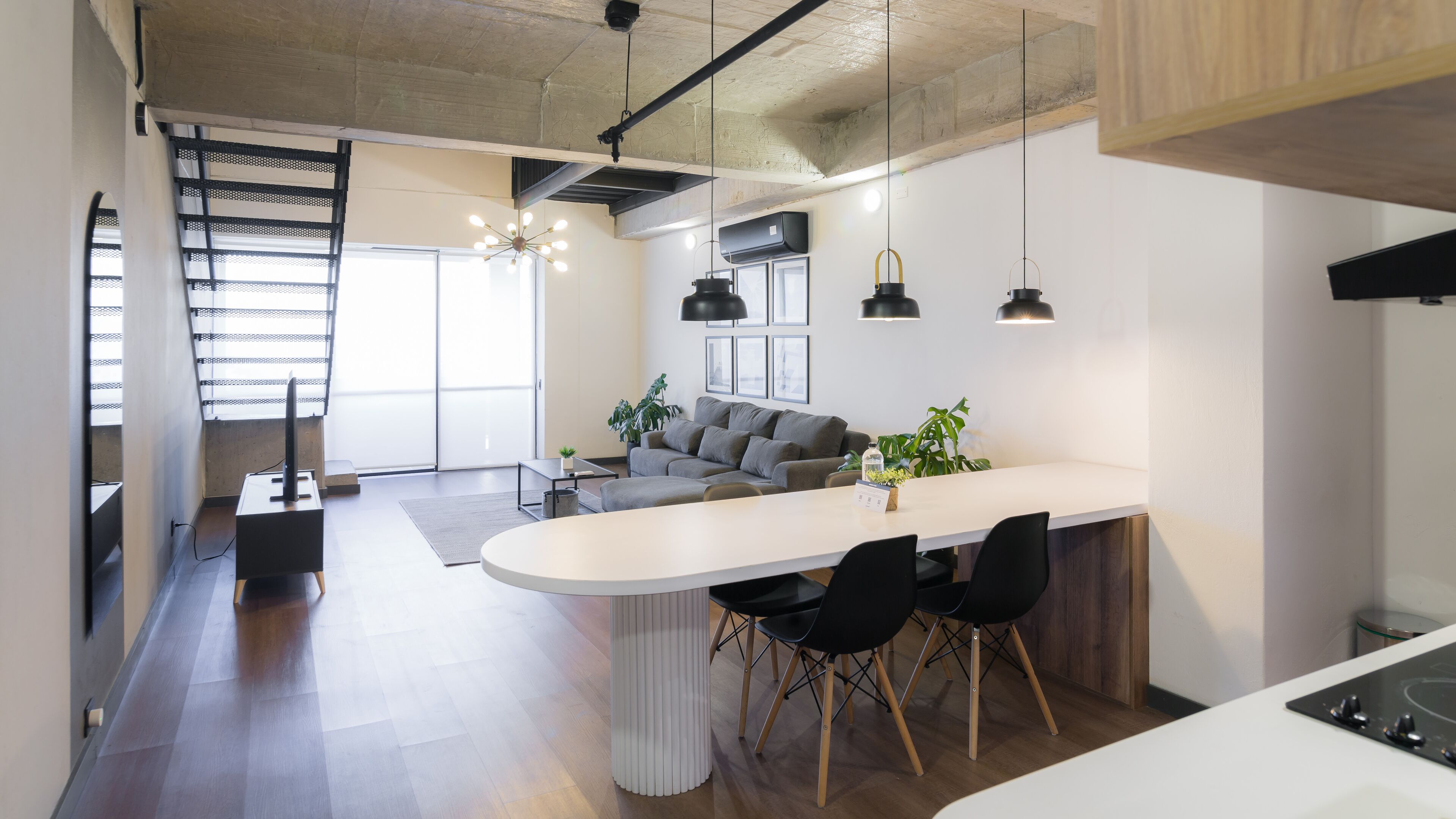 Eine moderne Küche mit Kochinsel, schwarzen Stühlen und einem grauen Sofa.