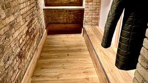 Un pasillo estrecho con suelo de madera y paredes de ladrillo visto.