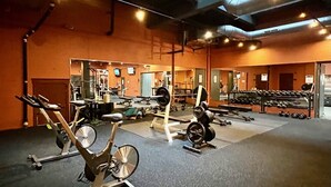Un gimnasio con equipo de ejercicio, espejos y una variedad de pesas.
