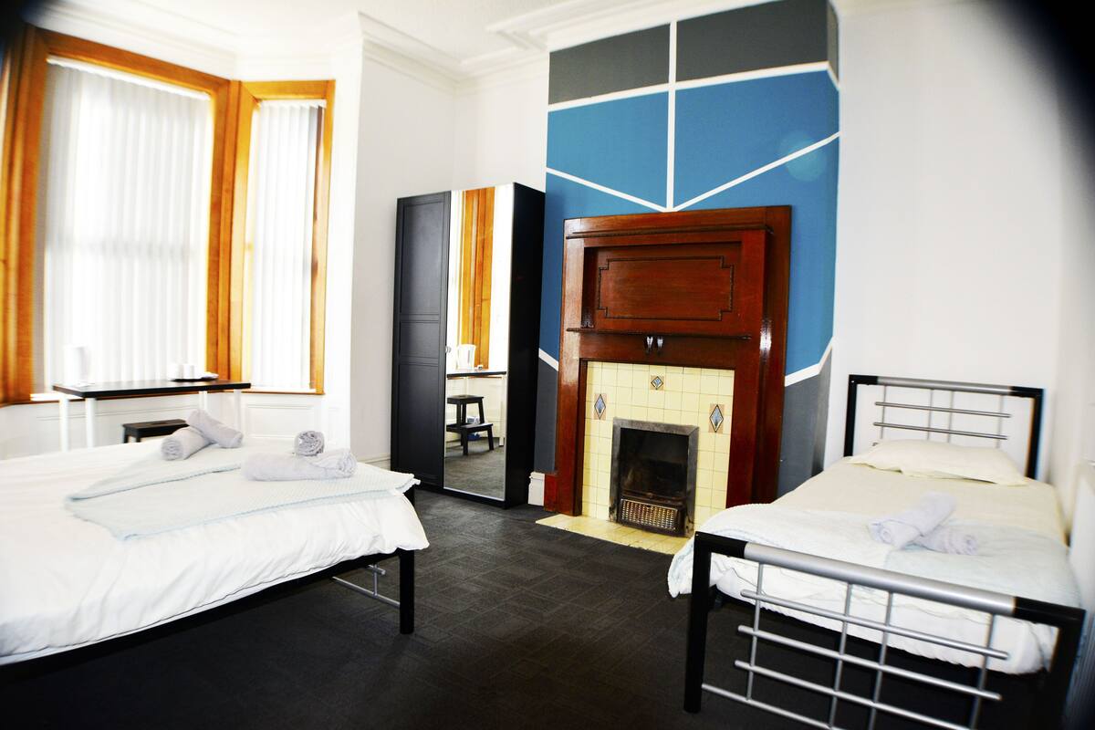 A hotel room with two beds, a fireplace, and a mirror.