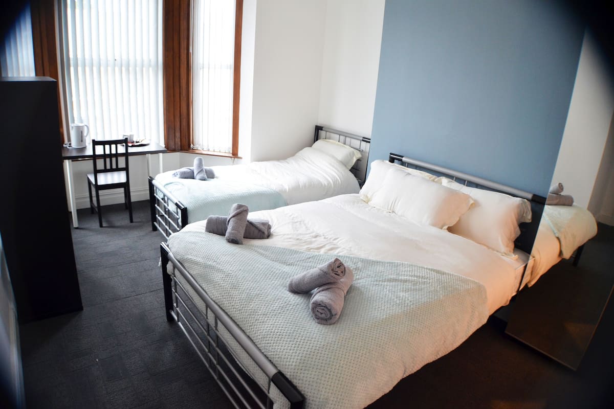 A hotel room with two beds, a desk, and a chair.