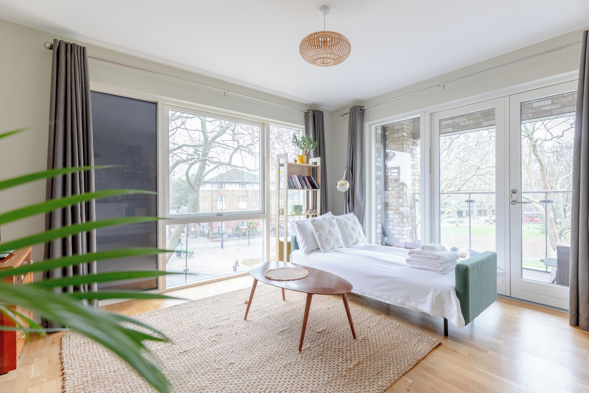 A bedroom with a bed, bedside table, and a view of the outside.