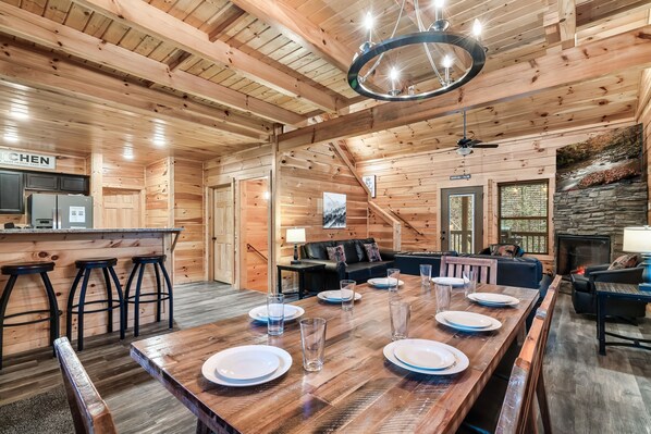 Ein Holzblockhaus-Interieur mit Essbereich, Barhocker, Kamin und Küchenzeile.