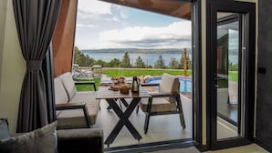 A modern room with a sliding glass door leading to a pool area, outdoor seating, and a view of a lake. - Lake Look Sapanca (Sapanca)