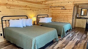 Una habitación de cabaña de madera con dos camas, una mesita y un espejo.