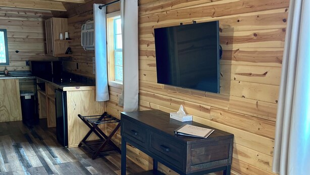 Un interior de madera con cocina, una mesa de comedor y un televisor de pantalla plana montado en la pared.