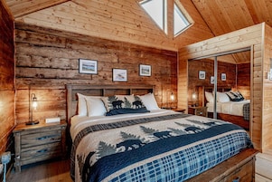 Dormitorio de cabaña de madera con una cama grande, paredes de madera y un tragaluz.