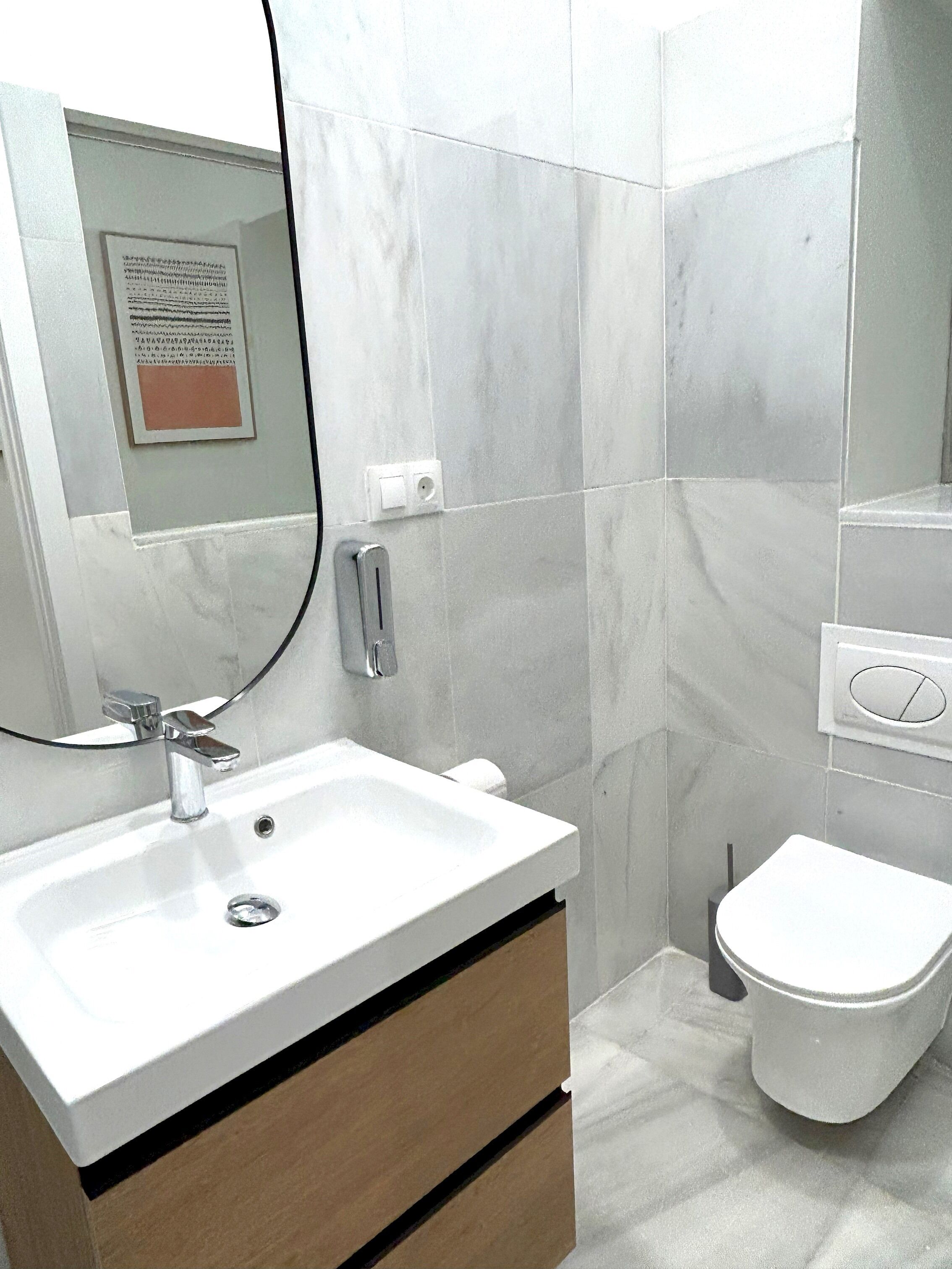 Un baño con un lavamanos blanco, un espejo, un inodoro y un aviso en la pared.