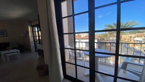 A room with a large window, a small table, a chair, and a wicker basket. - Apt. Brisa Marina  (Valle Gran Rey)
