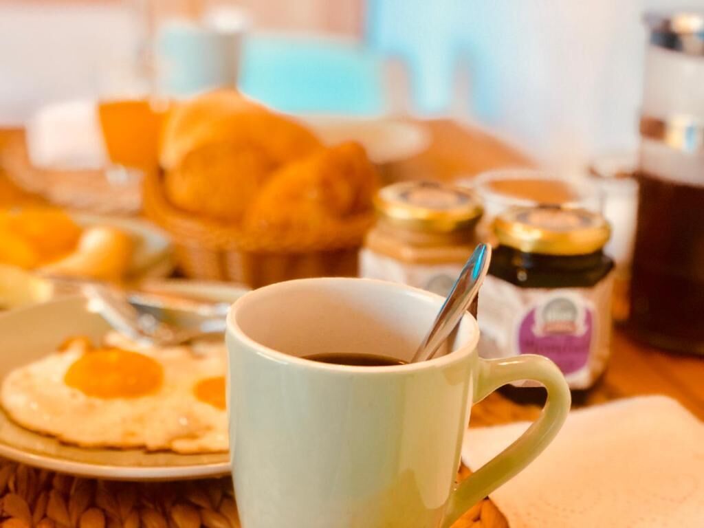 A breakfast setting with a cup of coffee, eggs, and pastries.