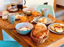 Una mesa de desayuno con diferentes alimentos, como huevos, pan y fruta.