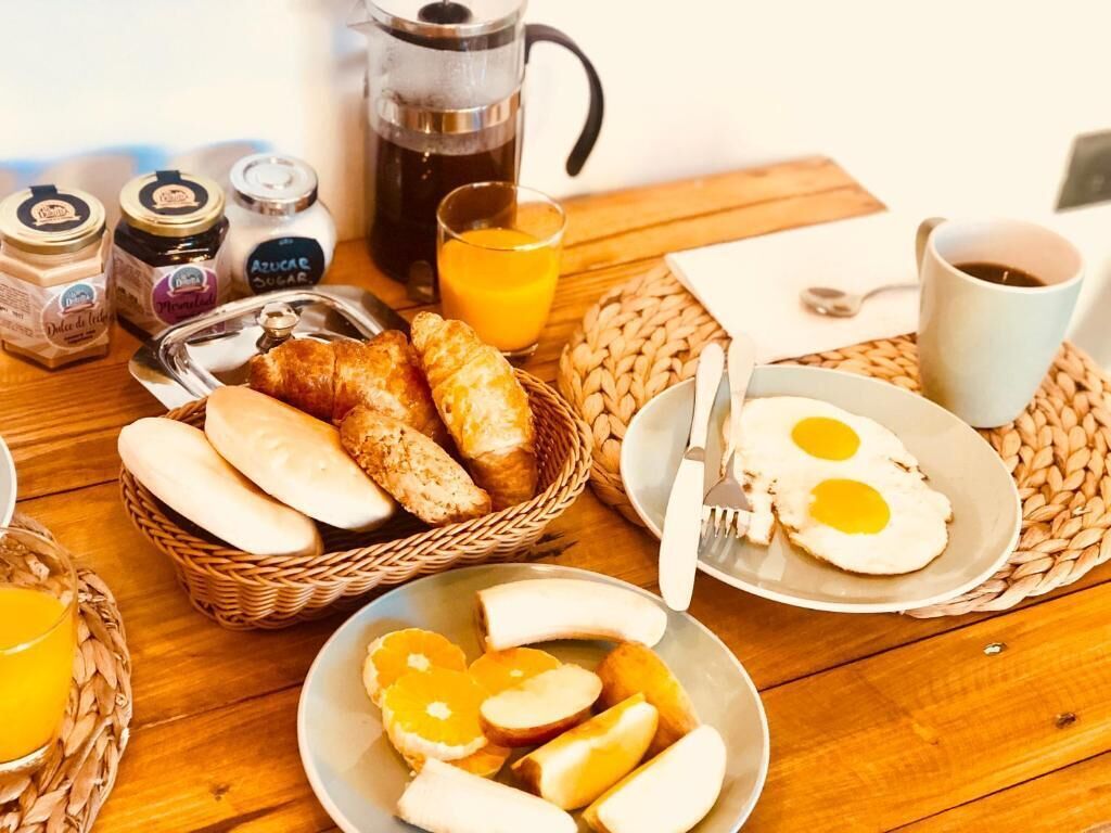 A breakfast table with bread, eggs, and orange juice.