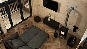 Una habitación acogedora con sofá, televisión, chimenea y un ventanal grande.