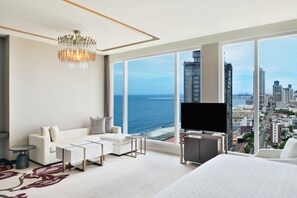 A modern hotel room with a large window, a chandelier, a sofa, a TV, and a bed. - Sheraton Colombo Hotel (Colombo)
