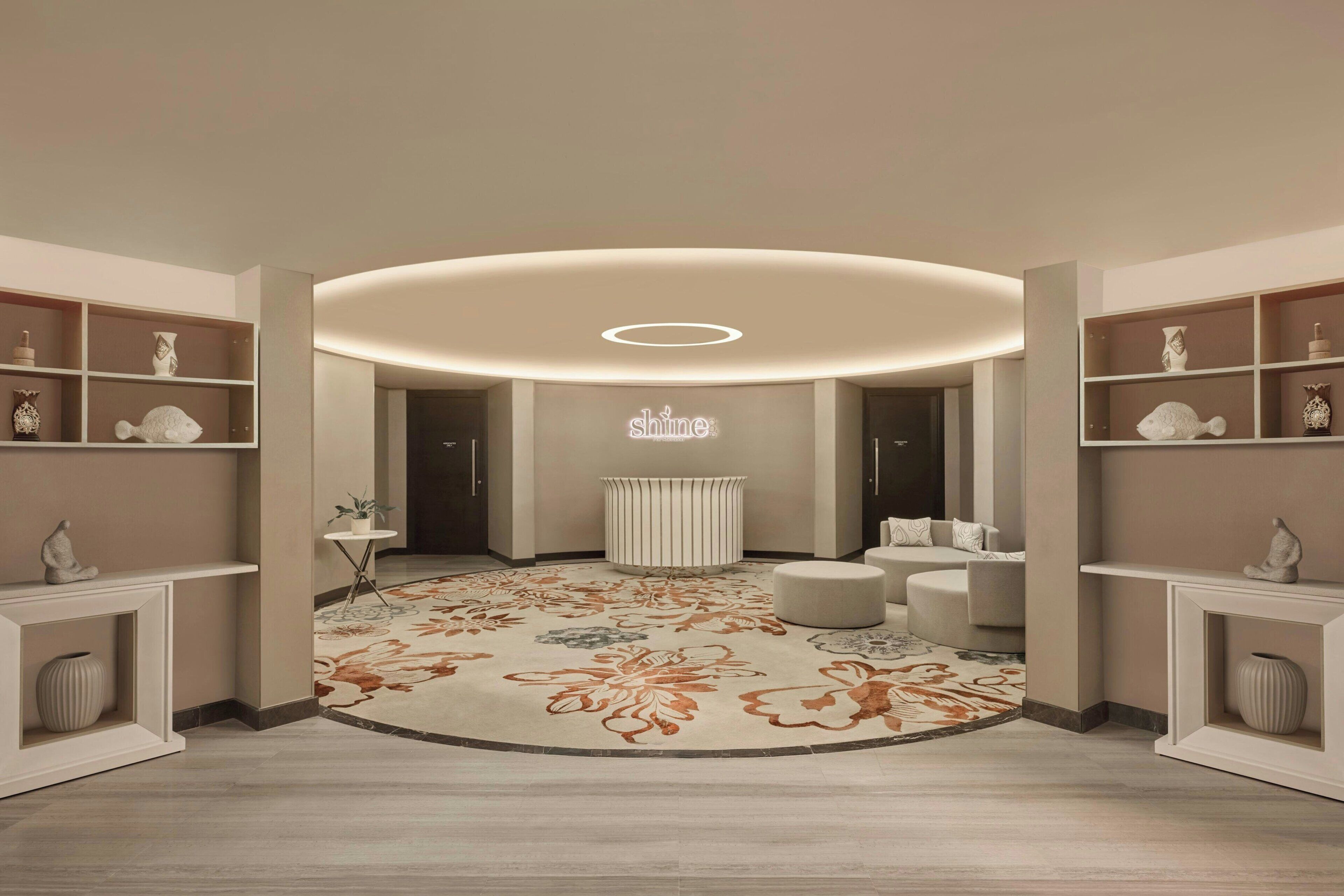 A modern interior with a central seating area, a decorative rug, and built-in shelving with various items.