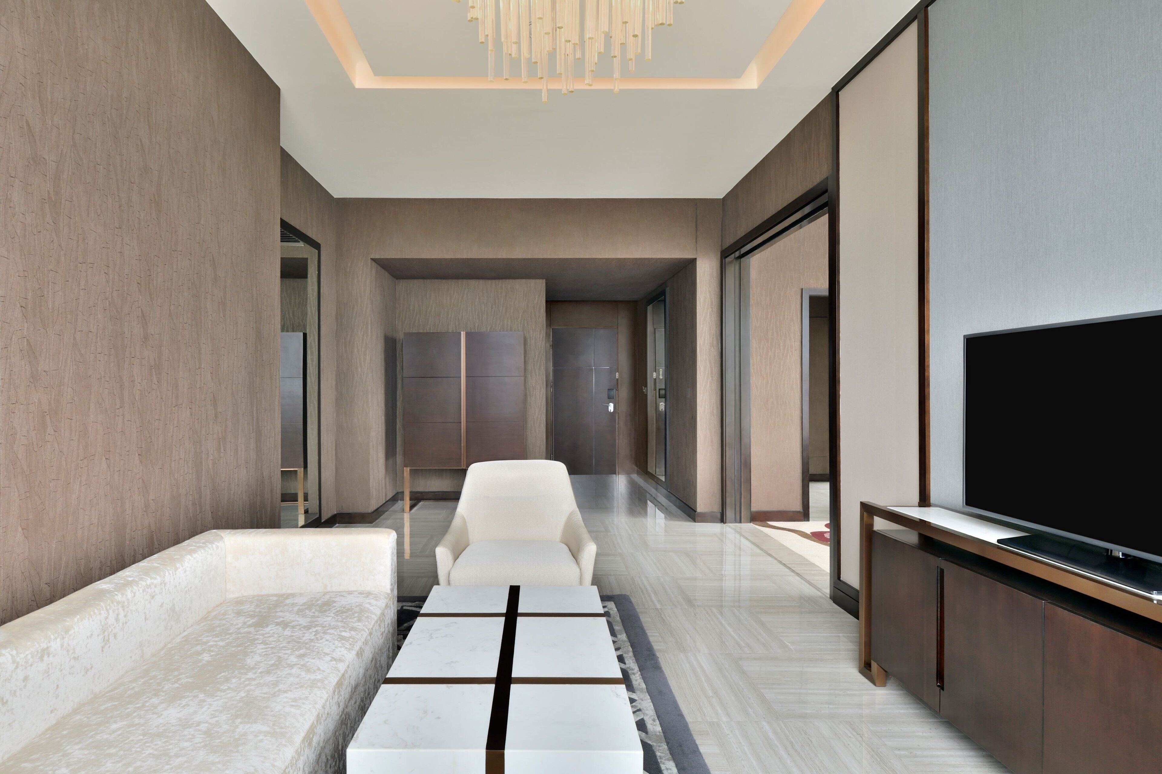 A modern hotel lobby with a seating area, a flat-screen TV, and a reception desk.