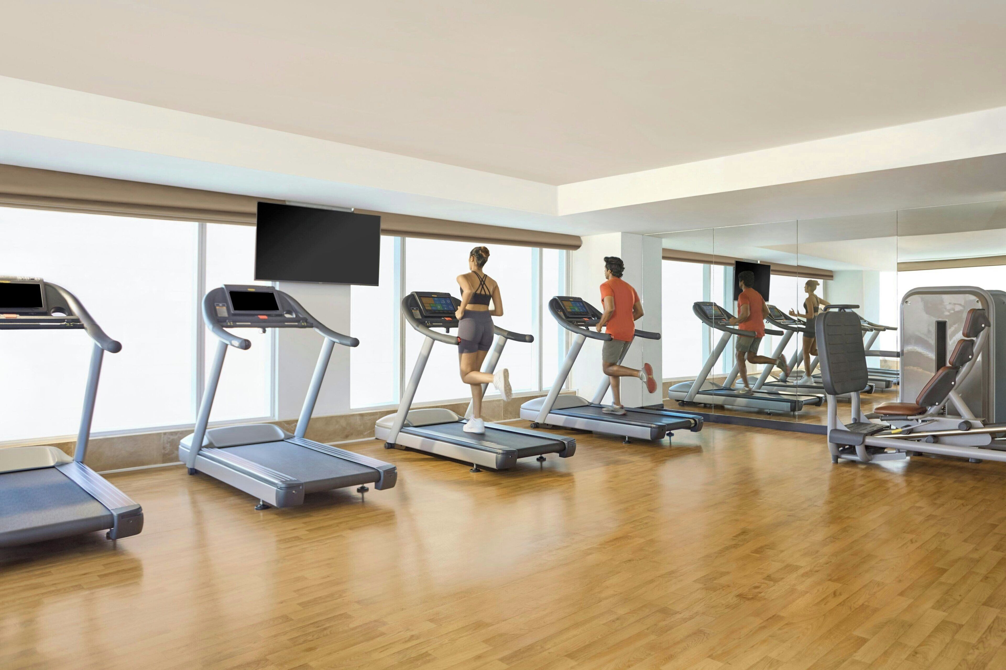 A gym with treadmills, a weight bench, and a mirror.