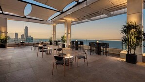 A rooftop terrace with outdoor seating, a view of the city skyline, and a large potted plant. - Sheraton Colombo Hotel (Colombo)
