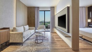A modern hotel room with a sofa, a small round table, a TV, and a balcony with a view. - Courtyard by Marriott Gorakhpur (Gorakhpur)