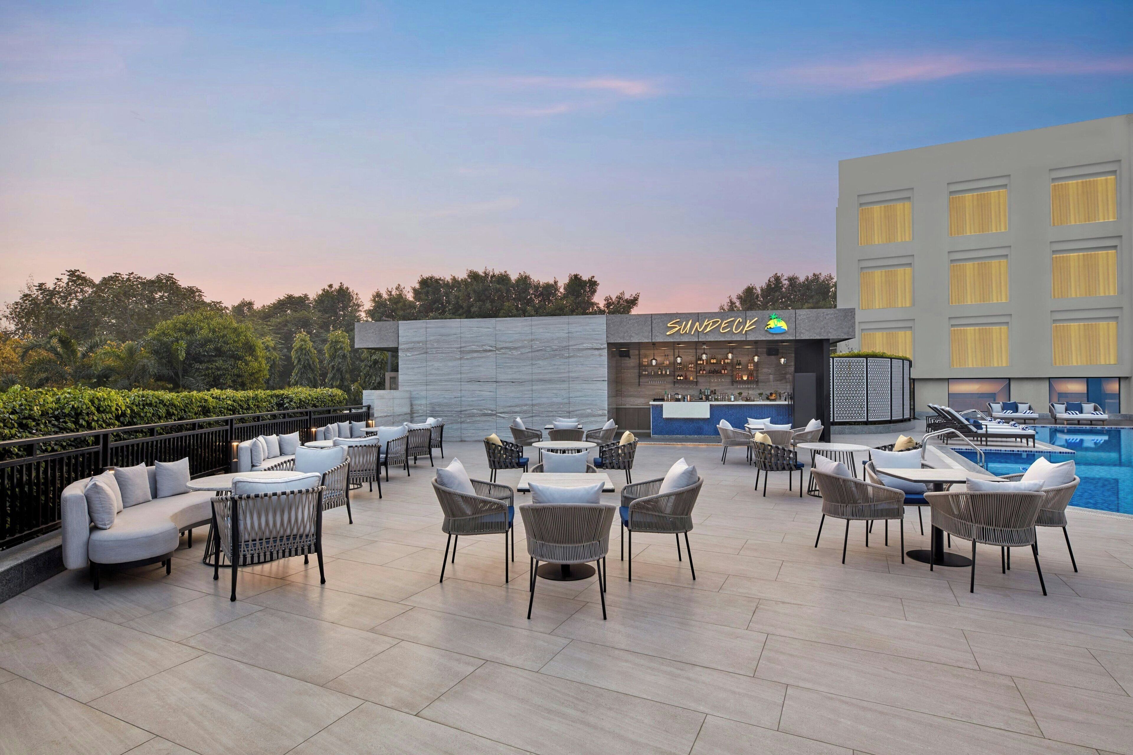 A rooftop bar with outdoor seating and a pool.