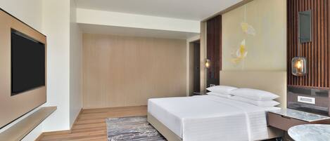 A modern hotel room with a large bed, a flat-screen TV, a marble side table, and a decorative wall panel.